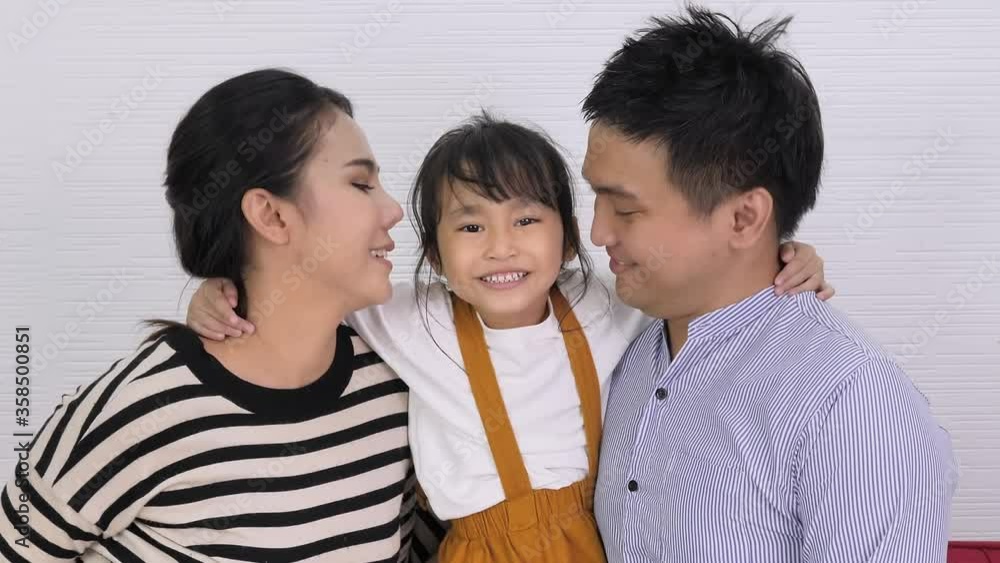 Asian family mother and father kissing child girl at home. Slow motion shot Asian family mother and father kissing child girl at home. Slow motion shot