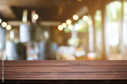 Empty wooden table space platform and blurred restaurant or coffee shop background for product display montage. © qOppi