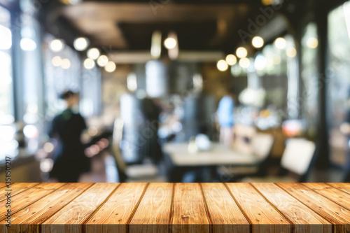 Empty wooden table space platform and blurred restaurant or coffee shop background for product display montage.