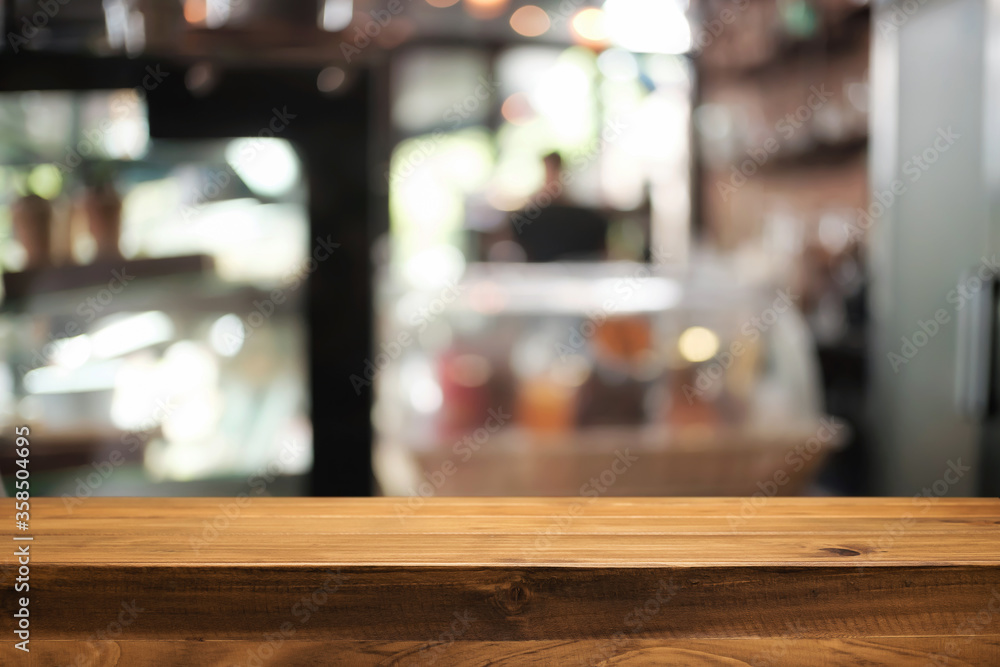 Empty wooden desk space platform over blurred restaurant or coffee shop background for product display montage.