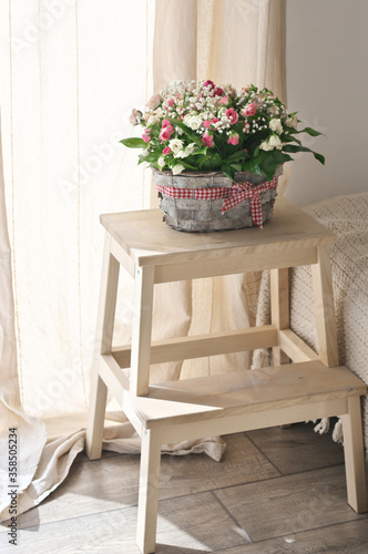 Flowers bouquet in basket against curtains