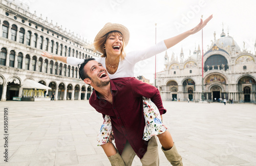 Beautiful couple in love having fun embracing and laughing doing piggyback ride at holiday in Venice, Italy on Piazza San Marco.