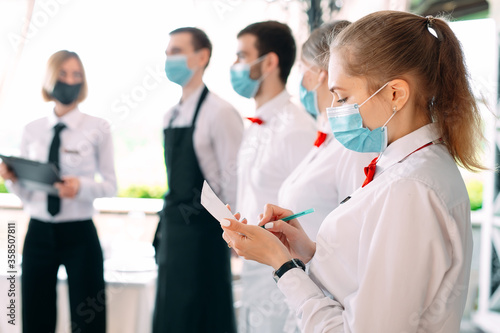 Employees of a Restaurant or Hotel in protective masks. End Of Quarantine. Restaurant Manager and his staff on the terrace. interaction with the chef in the restaurant.