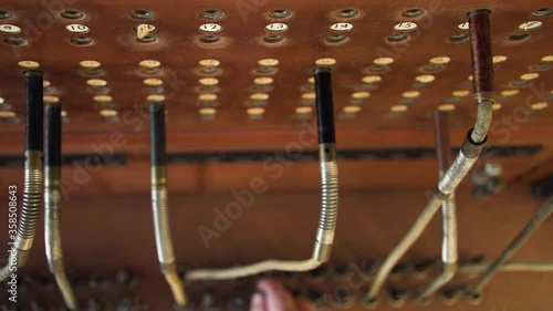 Manual switchboard operators hand plugging in jacks to connect calls, close up