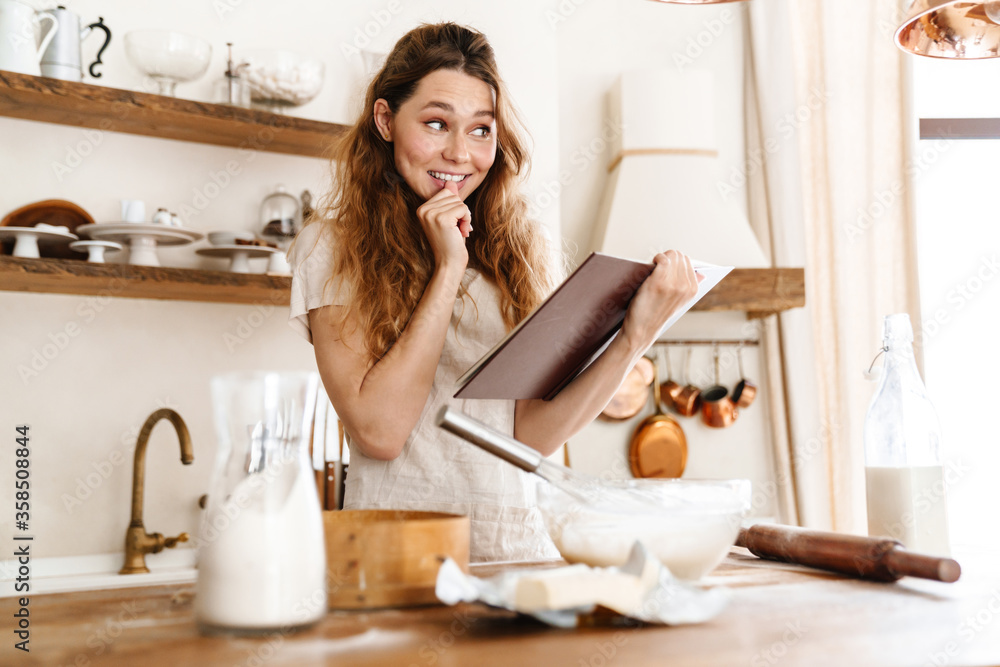 Attractive young cheerful girl baking at the kitchen Attractive young cheerful girl baking at the kitchen
