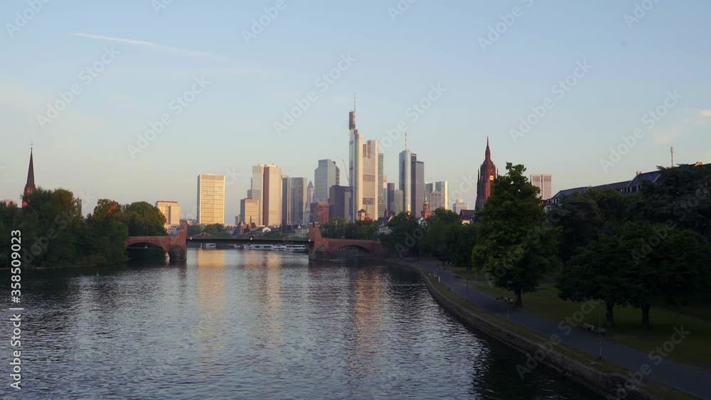 A beautiful shot of the frankfurt skyline during sunrise with a gentle reflection in the water A beautiful shot of the frankfurt skyline during sunrise with a gentle reflection in the water