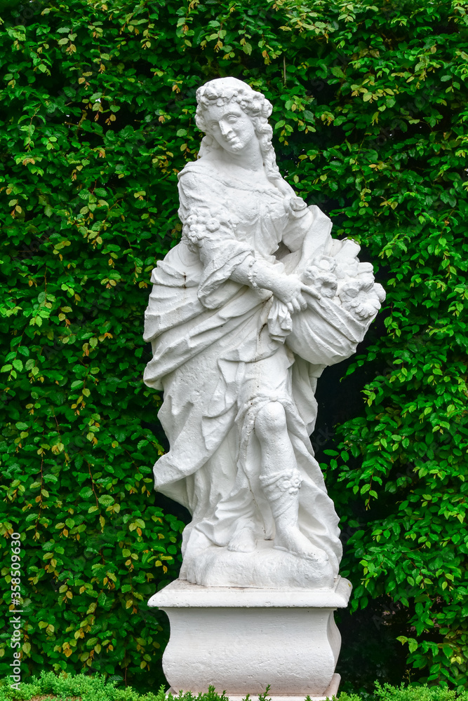 white statue of woman with green background, nature in park