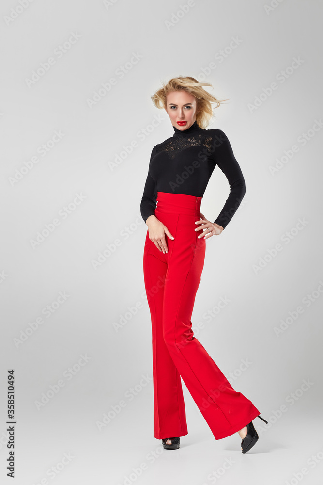 beautiful sexy blonde woman in black shirt and red pants on white background. beautiful sexy blonde woman in black shirt and red pants on white background.