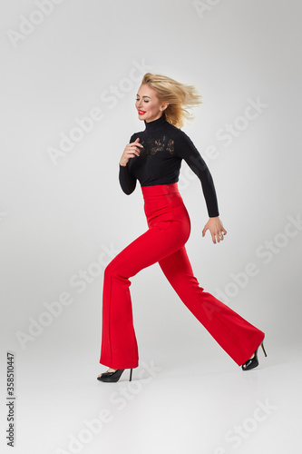 gorgeous sexy blonde woman in black shirt and red pants on white background.