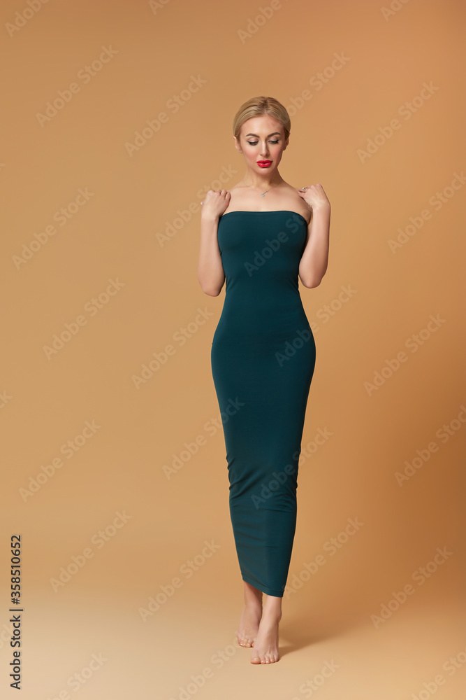stunning slim blonde woman in dark green dress on beige background. stunning slim blonde woman in dark green dress on beige background.