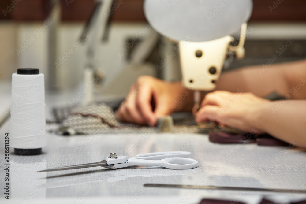Fototapeta premium girl seamstress sew on the sewing machine. Women's hands sewing on the sewing machine. Tailoring process