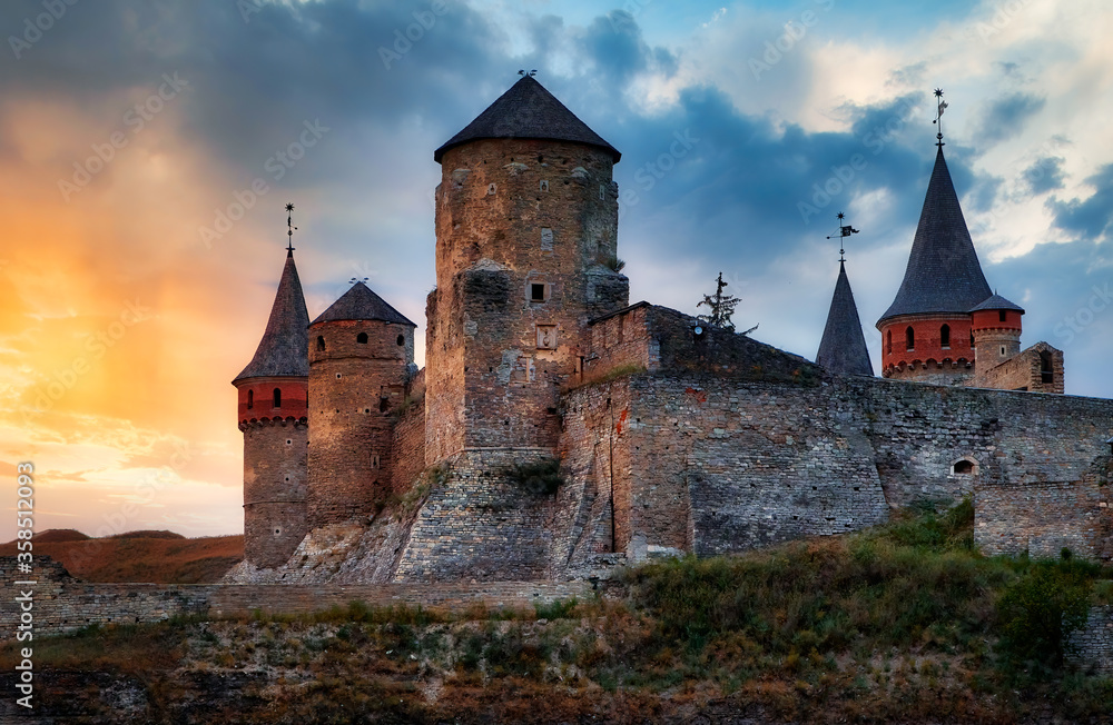 Kamianets Podilskyi old medieval fortress Ukraine. Famous fortified historic building tower exterior panorama. Sunset sky vivid colors