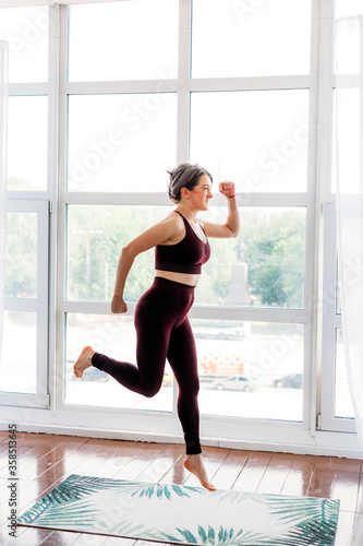 Girl does exercises, stretching, yoga, on a rug near the window, yoga suit, body, slimness and health