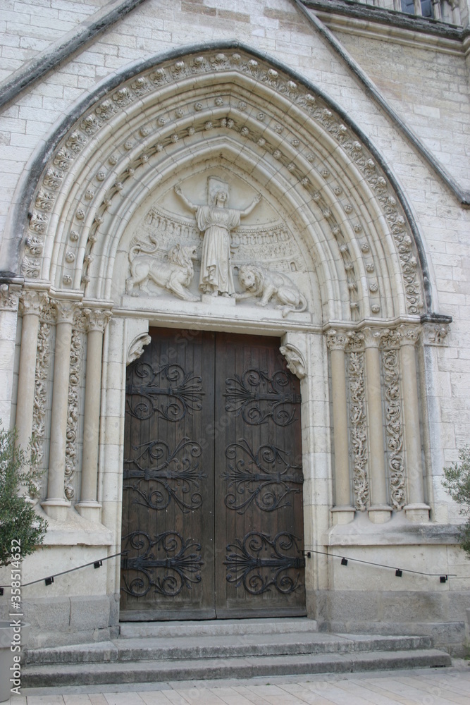 Decorated door of a French church welcoming visitors and believers