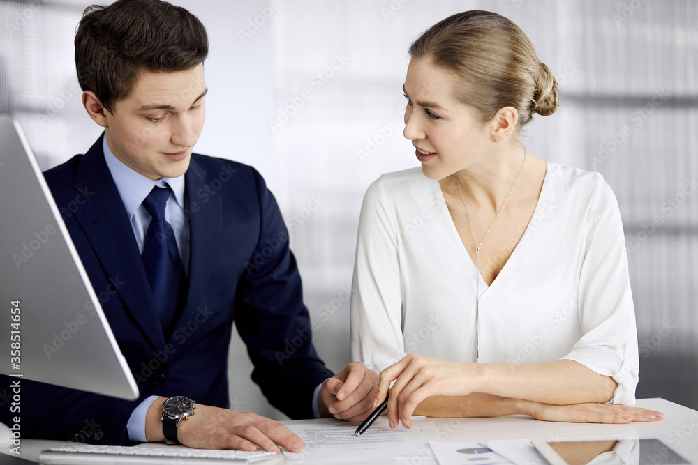 Business people discussing something while sitting in office. Focus at businesswoman while talking to her male colleague. Teamwork and meeting concept Business people discussing something while sitting in office. Focus at businesswoman while talking to her male colleague. Teamwork and meeting concept