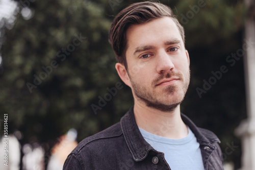 Young casual handsome man looking at the camera, outdoors in a park