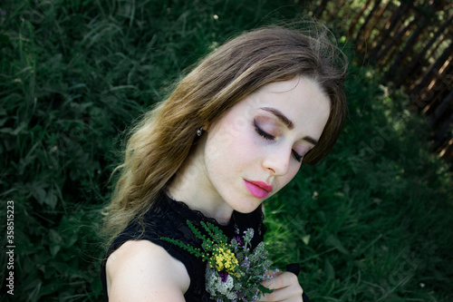 Portrait of a girl in the grass with a bouquet of dried flowers in the Gothic  mystical style.