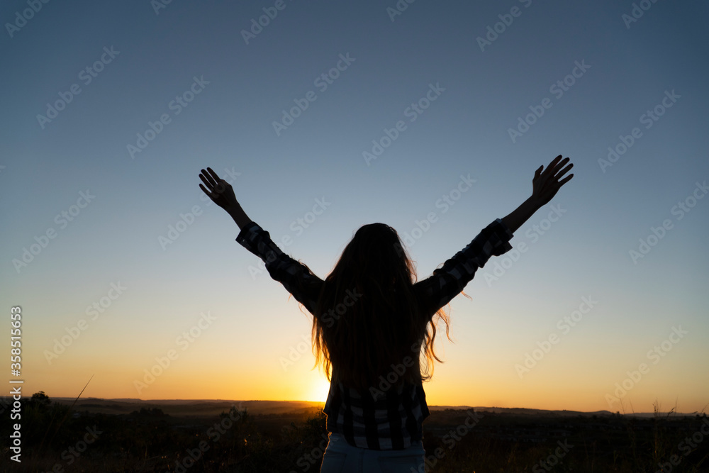 Woman with loose hair raising arms to the sky