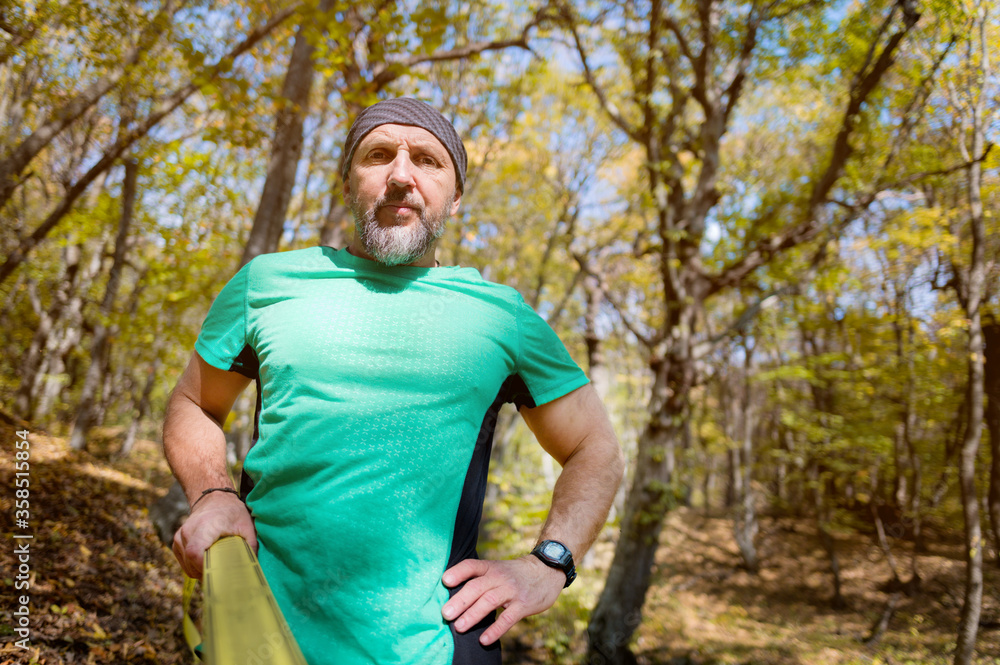 Portrait of a mature sports man with a beard next to a stretched slackline in the autumn forest in the afternoon. the concept of sports after 40 years Portrait of a mature sports man with a beard next to a stretched slackline in the autumn forest in the afternoon. the concept of sports after 40 years