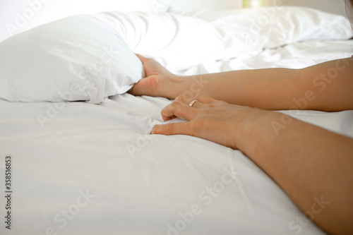 Woman hand with sex orgasm gesture hand grasp on white bed sheet.