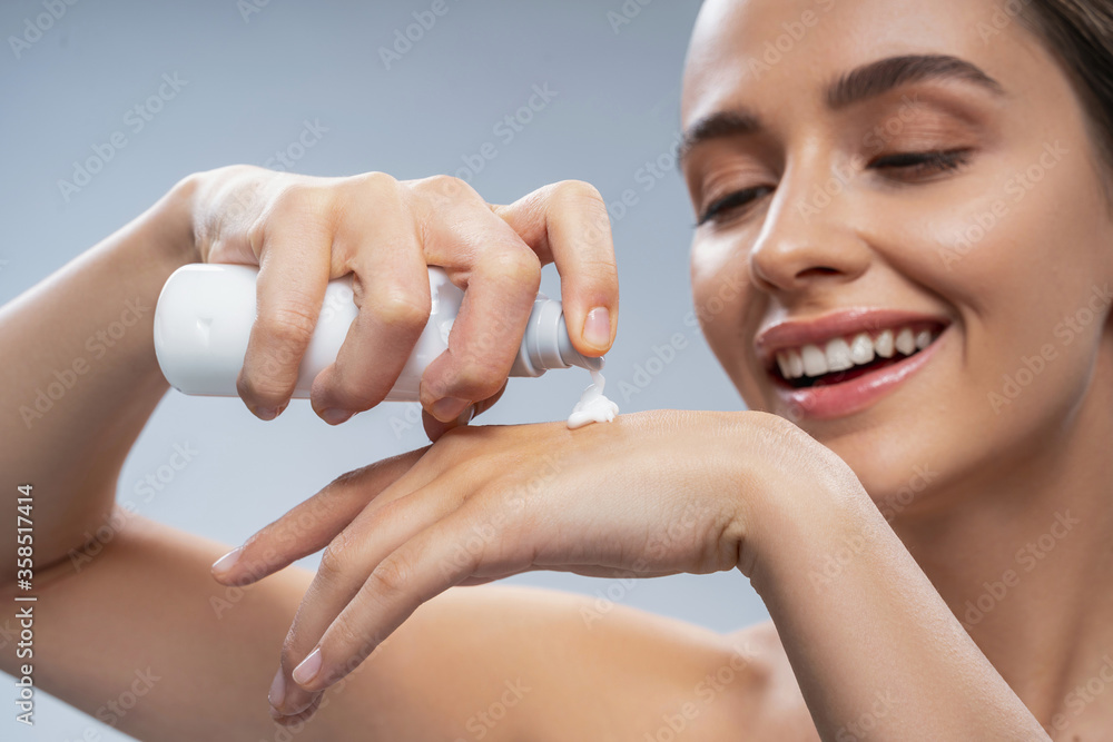 Happy young pretty woman using hand cream