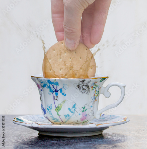 Dunking a biscuit in a cup of tea, with the resulting tea splashing out.