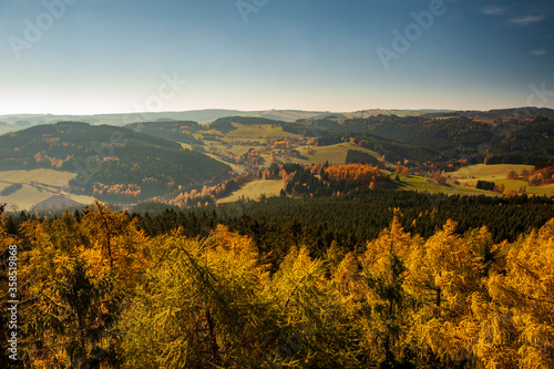 Sunset over autumn forest  fields and meadow in backlight. Evening sunbeams on meadow. Warm sun light in countryside of Bohemian Moravina Highlands        r Hills  Vysocina  Czech Republic.