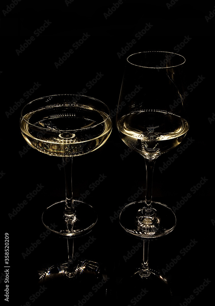 .two glasses with white wine on a black background .two glasses with white wine on a black background