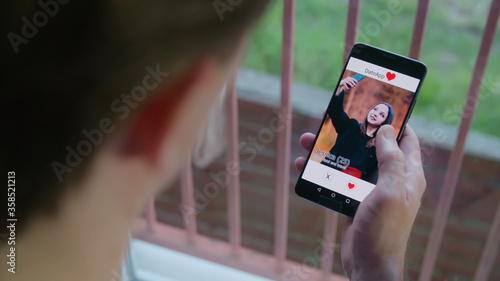 Obraz na plátně Male person looking at the female dating app profile on smartphone