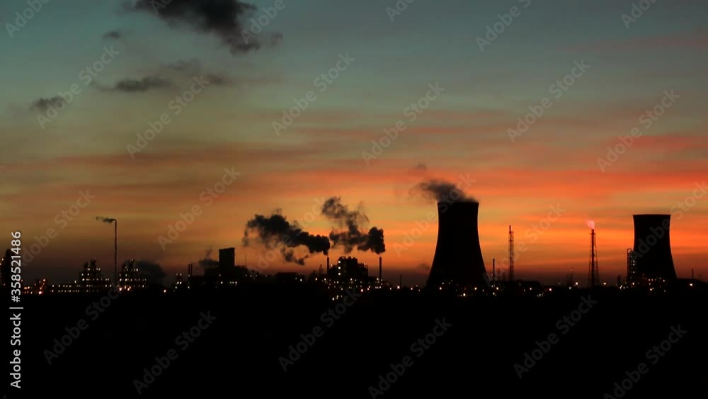 Cooling towers at oil refinery with steam. Sun setting sky. Time lapse Cooling towers at oil refinery with steam. Sun setting sky. Time lapse