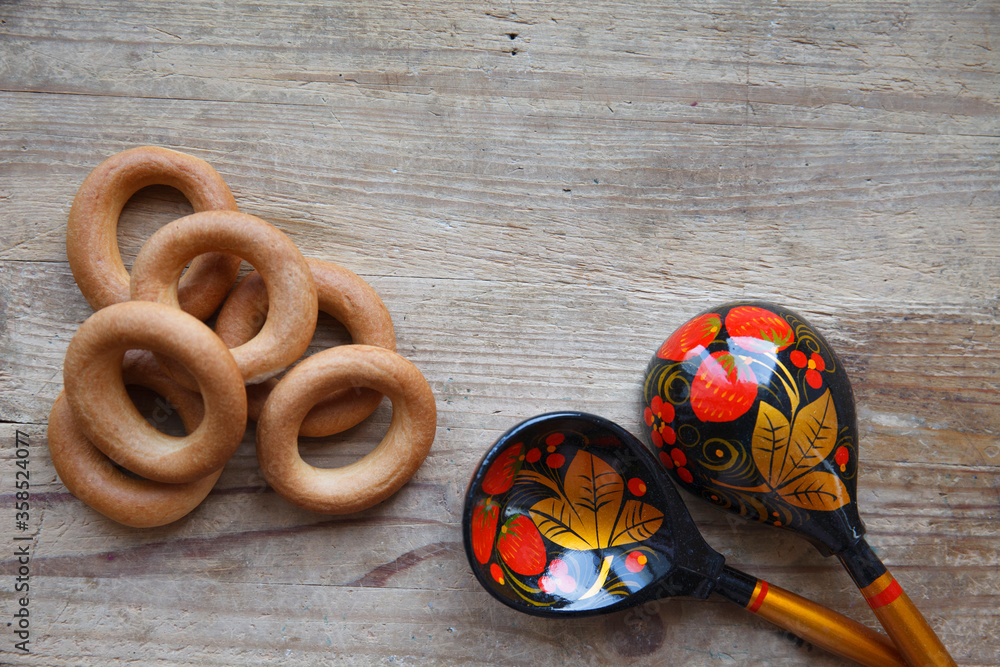 Russian folk background with Khokhloma painting spoons and bublik on wooden, place for text Russian folk background with Khokhloma painting spoons and bublik on wooden, place for text