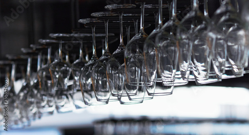 Wallpaper Mural Many empty wine glasses hanging upside down in a row on a special rack over the counter of a bar. Torontodigital.ca