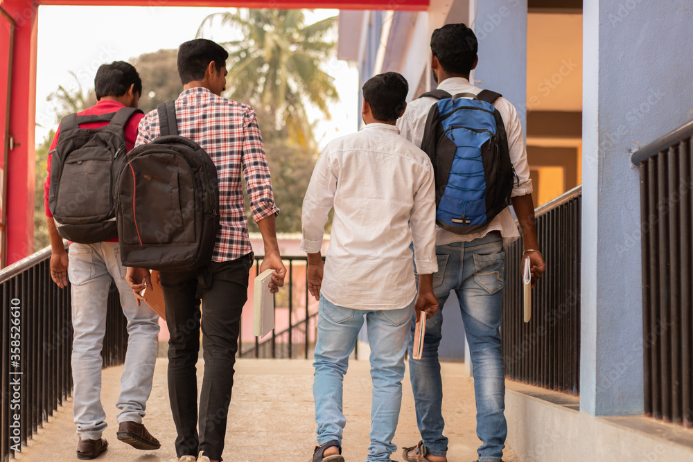 Rear view, group of students going back to college - Friends walking in university college campus - Education, friendship, togetherness, lifetyle concept