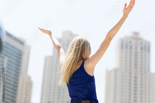 Photography Positive young carefree woman celebrating success in the city with arms raised up during sunny summer day