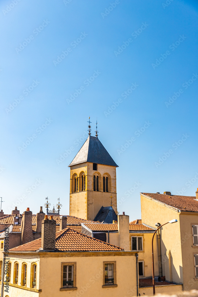Fototapeta premium Buildings with red roofs and Presbyterian church with tower in the background in Metz, France