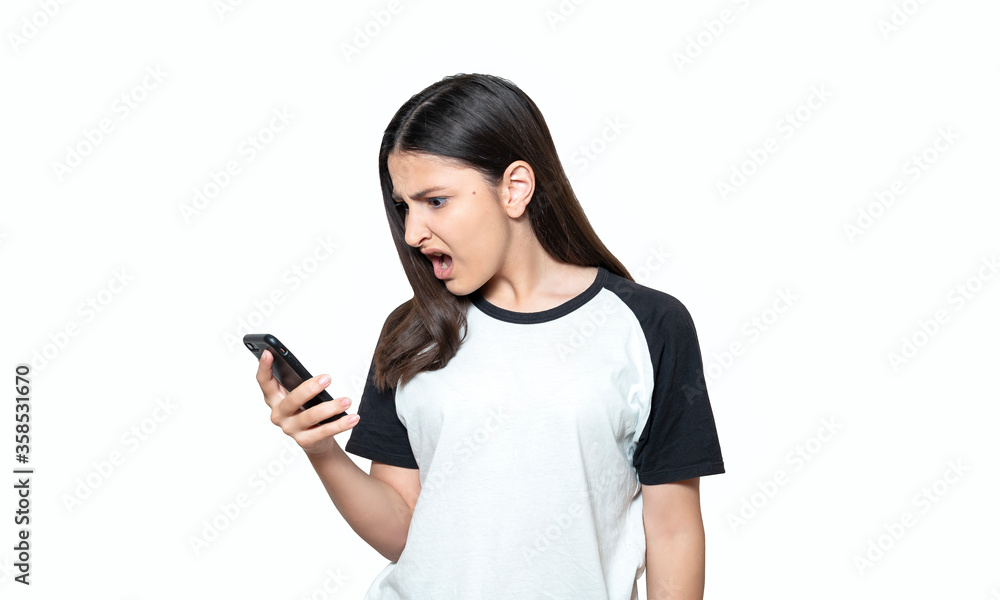 Annoyed angry young girl mad about spam message stuck phone looking at smartphone isolated on white background, furious teen girl having problem with cellphone irritated by broken mobile. Annoyed angry young girl mad about spam message stuck phone looking at smartphone isolated on white background, furious teen girl having problem with cellphone irritated by broken mobile.