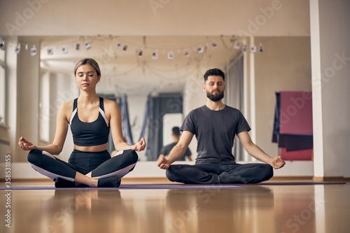 Two sporty people sitting on the yoga mats