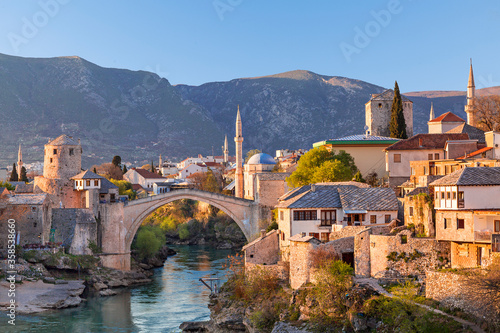 Skyline of Mostar with the Mostar Bridge, houses and minarets, at the sunset in Bosnia and Herzegovina photo
