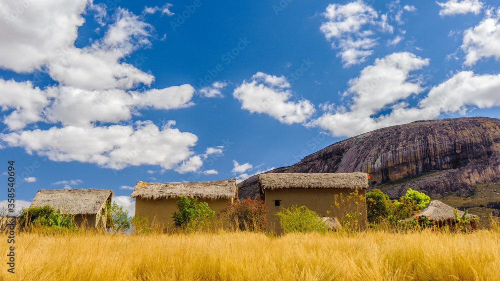 It's Composition of three houses neat the rock under the blue sky over the field It's Composition of three houses neat the rock under the blue sky over the field