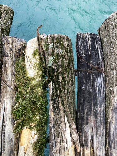 Old bridge over the river closeup. Textured boards with moss and cracks. Mountain river.