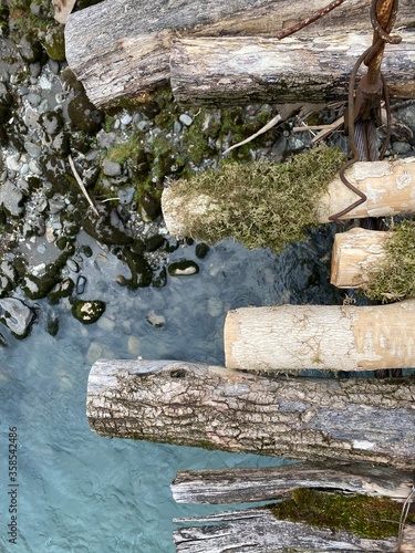 Old bridge over the river closeup. Textured boards with moss and cracks. Mountain river.