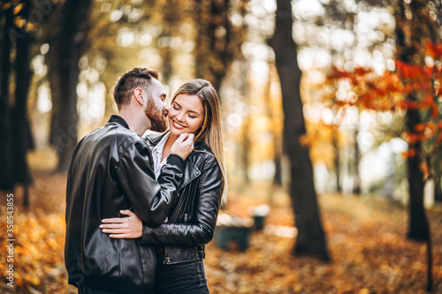 Man and woman hugging and smiling in the background of autumn park.