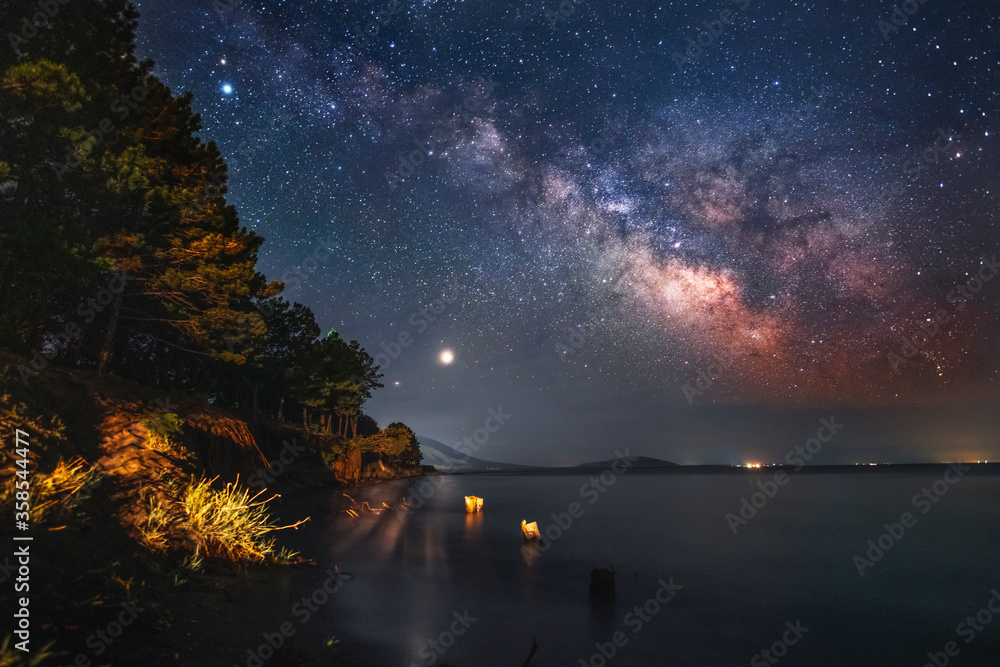 Beautiful starry sky with bright milky way galaxy over the lake. Night landscape . 