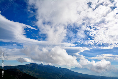 夏の青空に浮かぶたくさんの白い雲、深緑に覆われた南八ヶ岳。 The blue sky & white clouds & Yatsugatake mountain range covers in dark green.  © Sanae