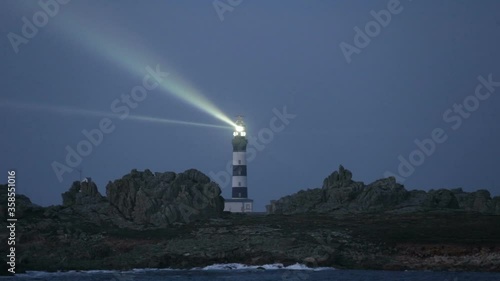 Créac'h lighthouse illuminated in evening with seagulls flying over the sky, the most powerful in the world, Ushant island (aka Ouessant), Brittany, France