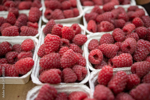  raspberries in containers on a stall forming a background