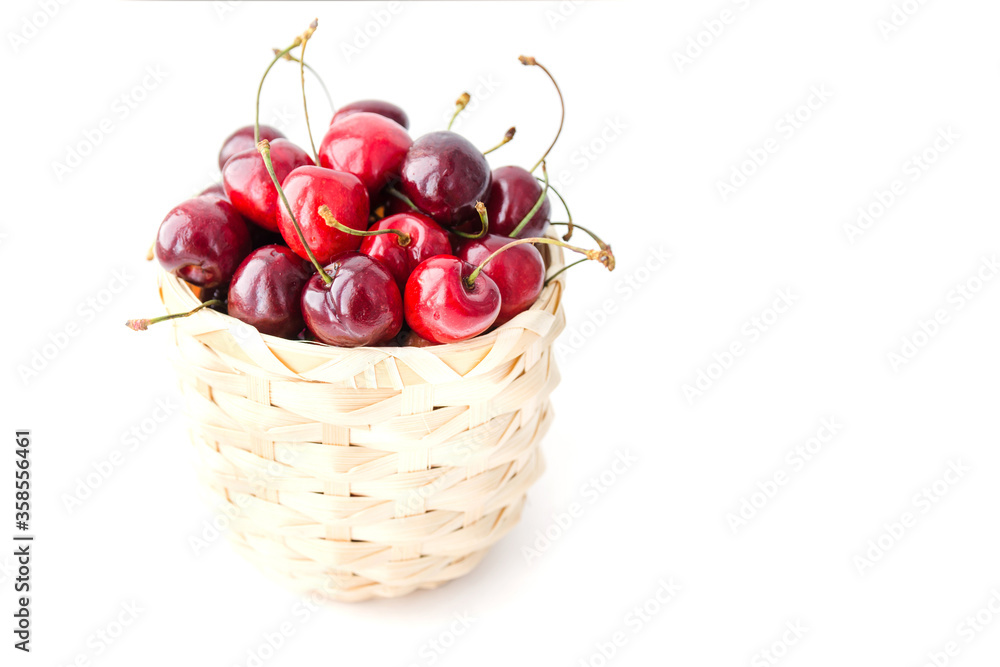 Ripe cherry berries in the wooden basket isolated on the white background. Copy space. Selective focus Ripe cherry berries in the wooden basket isolated on the white background. Copy space. Selective focus