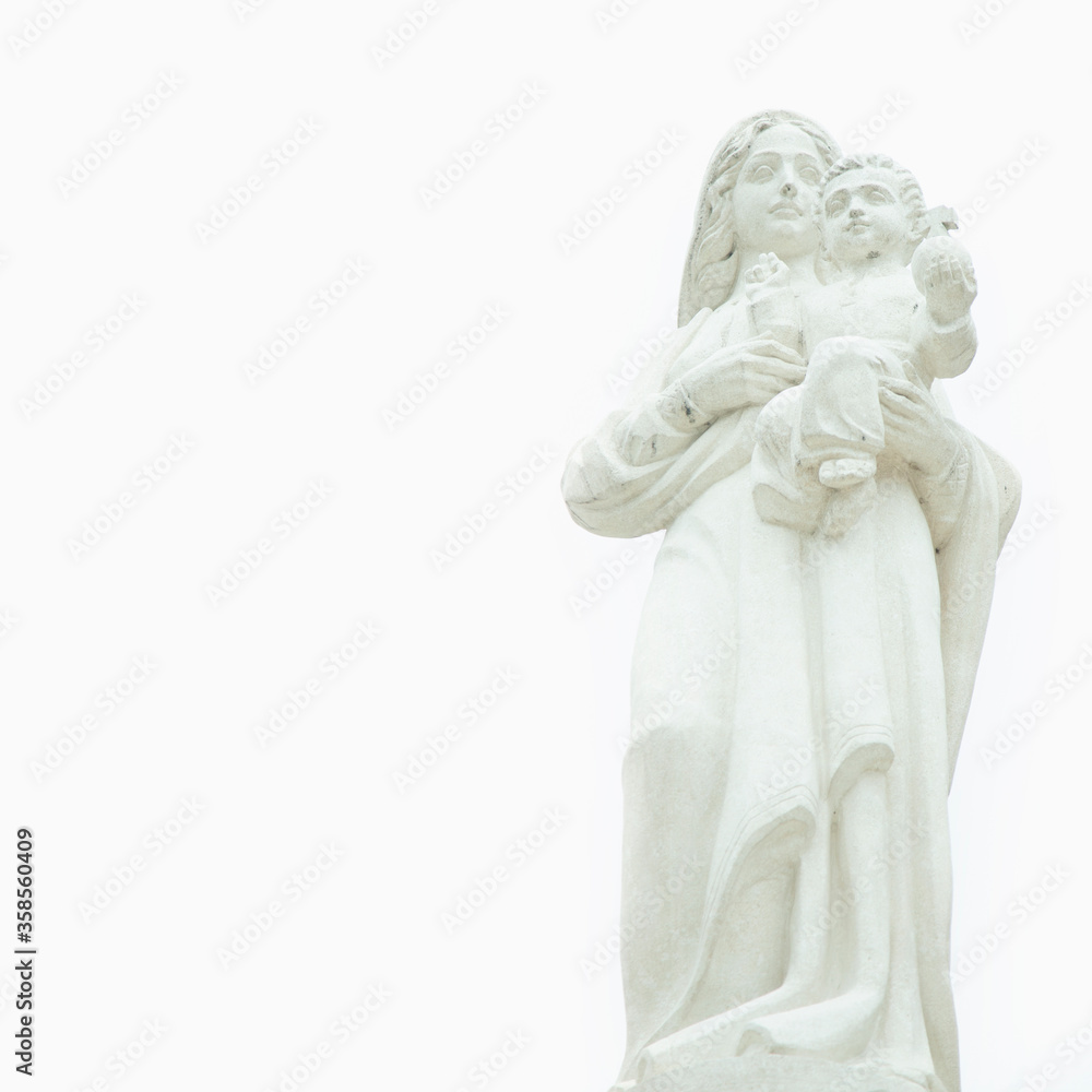 Ancient stone statue of Virgin Mary with the baby Jesus Christ against white background. Religion, faith, eternal life, God concept.