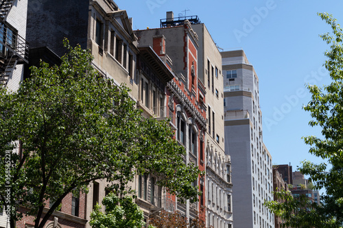 Fototapeta Naklejka Na Ścianę i Meble -  Row of Colorful Old Buildings and Skyscrapers on the Upper East Side of New York City with Green Trees