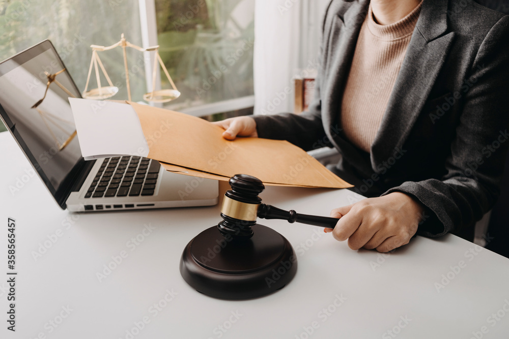 Justice and law concept.Male judge in a courtroom with the gavel, working with, computer and docking keyboard, eyeglasses, on table in morning light Justice and law concept.Male judge in a courtroom with the gavel, working with, computer and docking keyboard, eyeglasses, on table in morning light